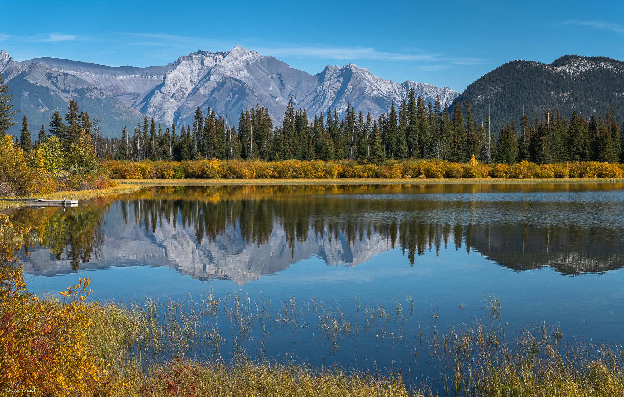 תמונת טבע אגם עם יער ומאחורי היער יש הרים
