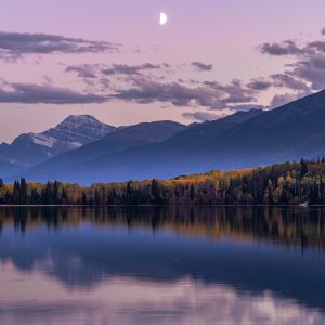 גווני העצים המשתנים בסתיו בהשתקפות מרהיבה על אגם בשקיעה סגלגלה , אלברטה ,קנדה .
