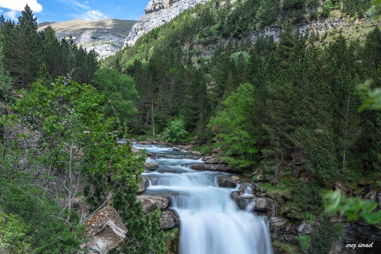 סידרת מפלים בין הרי הפירנאים בין עצים ירוקים